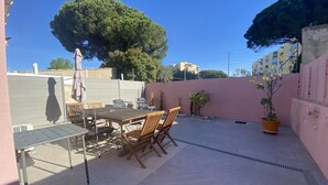 A patio with a table and chairs, a potted plant, and a large tree. - Large house with AC in the center - 8 guests (Le Grau-du-Roi)