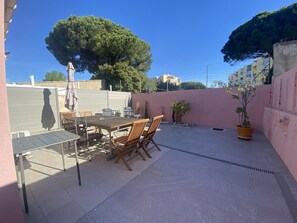 A patio with a table and chairs, a potted plant, and a large tree. - Large house with AC in the center - 8 guests (Le Grau-du-Roi)