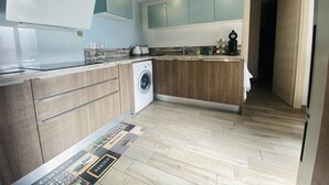 A modern kitchen with a washing machine, wooden cabinets, and a tiled floor. - Large house with AC in the center - 8 guests (Le Grau-du-Roi)