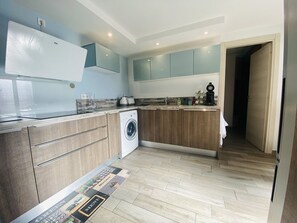 A modern kitchen with a washing machine, wooden cabinets, and a tiled floor. - Large house with AC in the center - 8 guests (Le Grau-du-Roi)