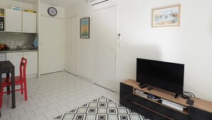 Ein kompakter Wohnraum mit Küchenzeile, Essbereich, Fernseher und einem gemusterten Teppich.