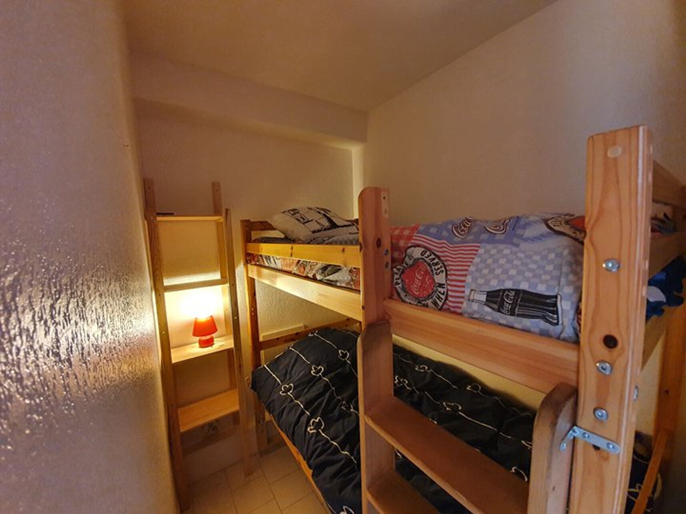 Ett rum med en våningssäng, en hylla och en lampa.