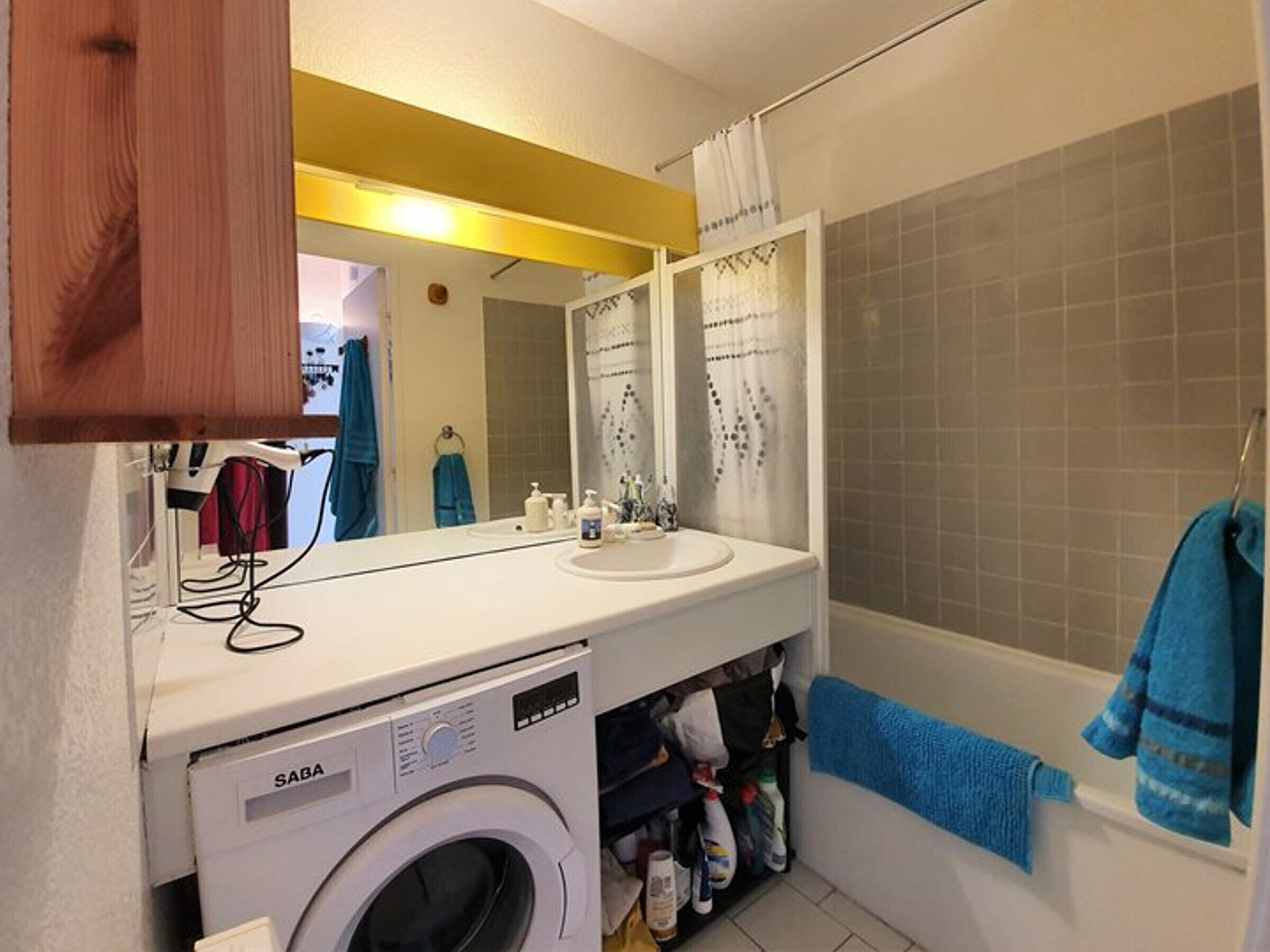 A compact bathroom with a washing machine, a sink, and a bathtub.