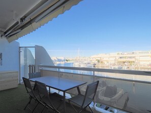 Uma varanda com mesa e cadeiras, com vista para uma marina com barcos e edifícios.