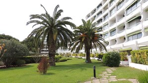 Un hotel con un giardino curato, palme e un viale in pietra.