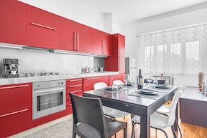 A modern kitchen with red cabinets, stainless steel appliances, and a dining area with a dark table and white chairs. - (duomo-navigli) dream flat dock free wifi & AC (Milano)