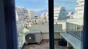Ein Balkon mit Blick auf moderne Gebäude, einer Toshiba-Klimaanlage und einer Betonbank.