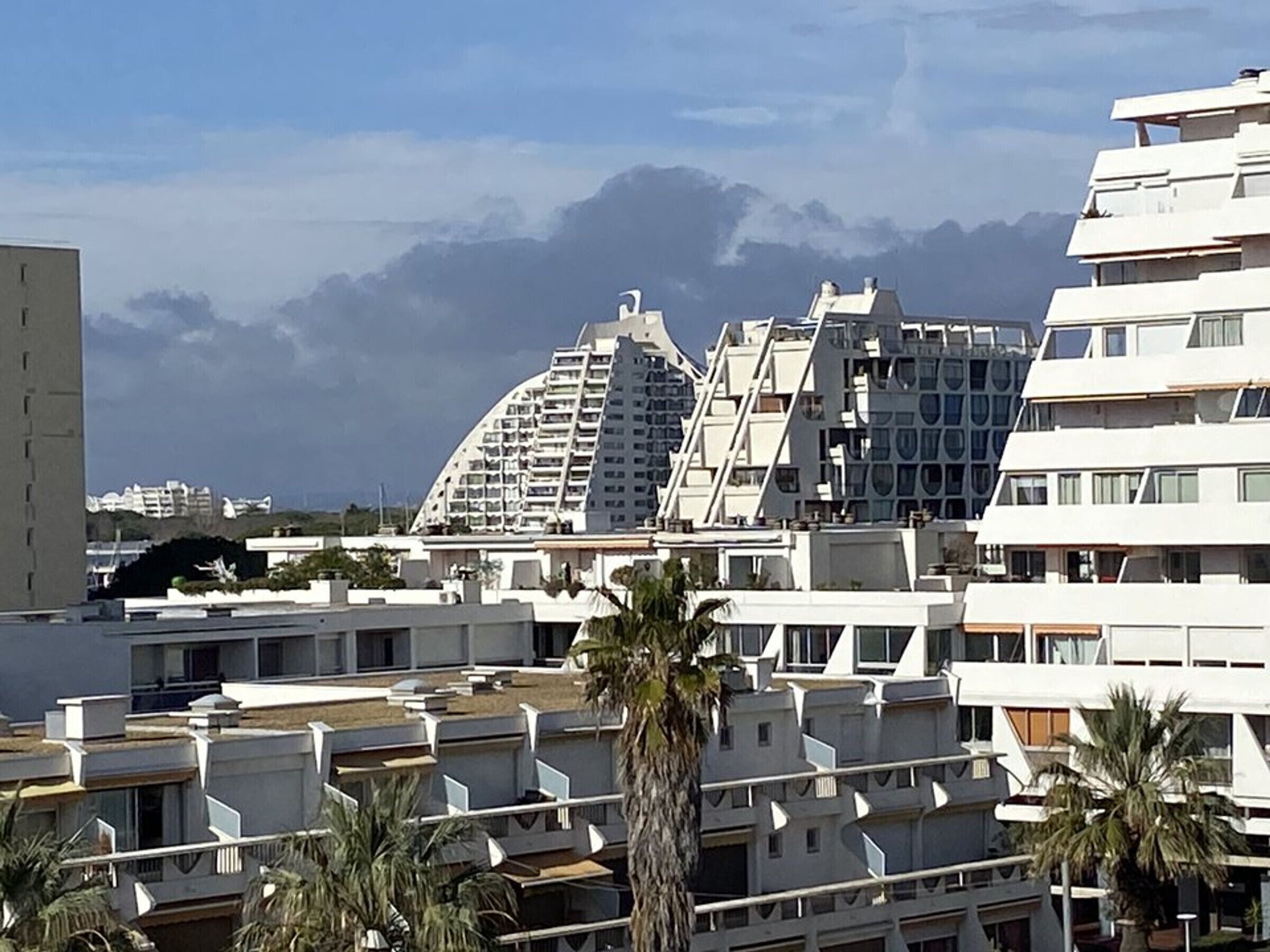 Ein modernes Gebäude mit einer gewölbten Fassade, mehreren Balkonen und Blick auf Berge.