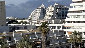 Ein modernes Gebäude mit einer gewölbten Fassade, mehreren Balkonen und Blick auf Berge.