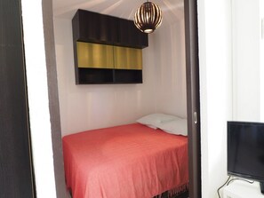 Ein Schlafzimmer mit einem Bett, einem Fernseher und einer Pendelleuchte.
