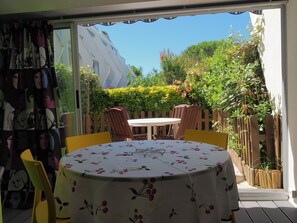 Eine Terrasse mit Tisch und Stühlen, ein Holzzaun und viel Grün.