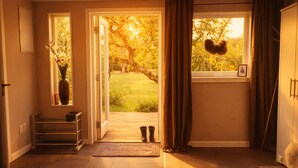 A hallway with a wooden door leading to a garden, a small shelf with a vase, and a framed picture on the wall. - Modern guesthouse close to sea, nature, golf, hiking & Kattegat Trail (Särö)