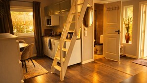 A compact living space with a kitchen, dining area, and a staircase leading to a bathroom. - Modern guesthouse close to sea, nature, golf, hiking & Kattegat Trail (Särö)