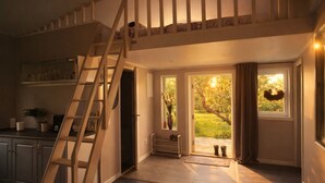 A spacious kitchen with a wooden staircase, a dining area, and a view of a garden through large windows. - Modern guesthouse close to sea, nature, golf, hiking & Kattegat Trail (Särö)