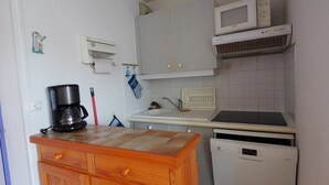 A compact kitchen with a wooden countertop, a coffee maker, a microwave, and a dishwasher. - Apartment near the beach - 4 guests (Le Grau-du-Roi)