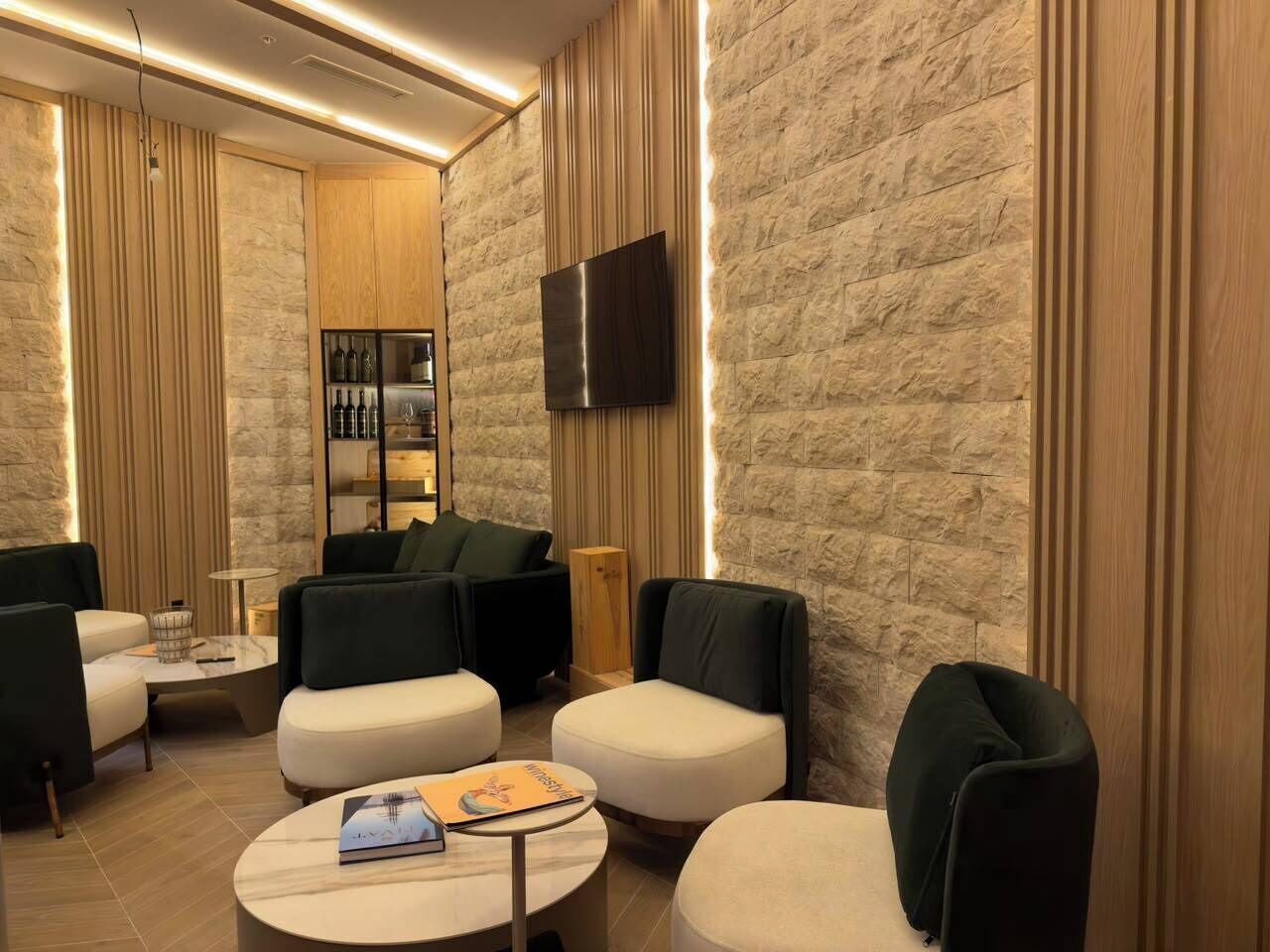 Un salón moderno con una pared de piedra, un televisor de pantalla plana y una zona de bar con botellas.