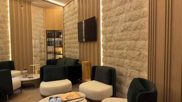 Un salón moderno con una pared de piedra, un televisor de pantalla plana y una zona de bar con botellas.