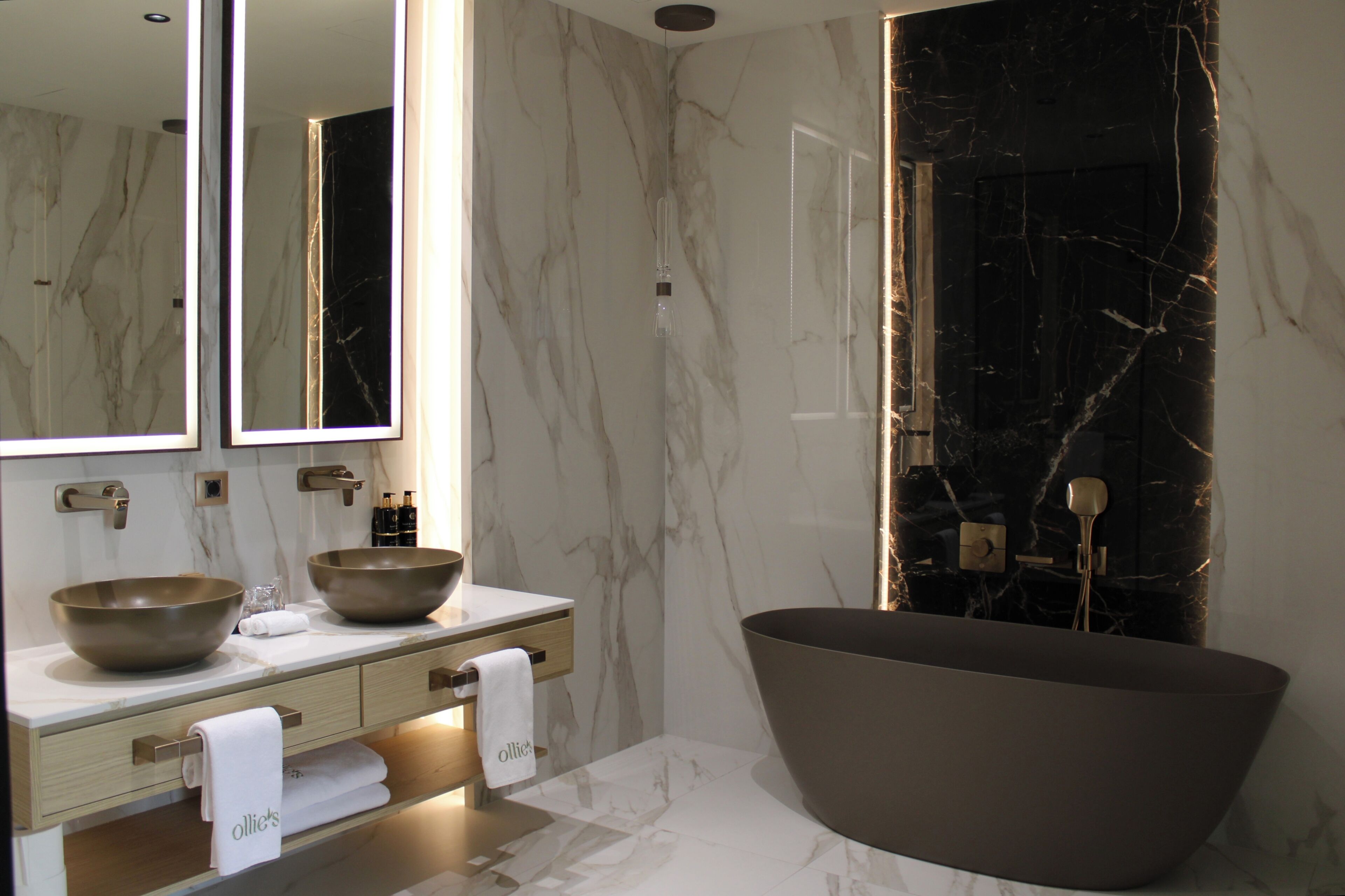 Une salle de bain moderne dotée d’une grande baignoire sur pieds, de deux vasques et d’un grand miroir.
