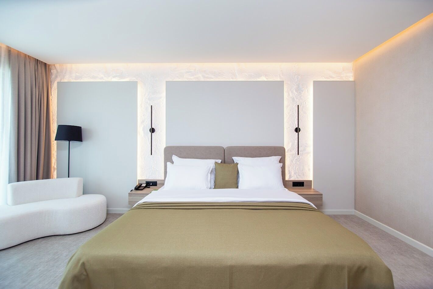 Una habitación de hotel con una cama, mesitas de noche, una lámpara y una silla.