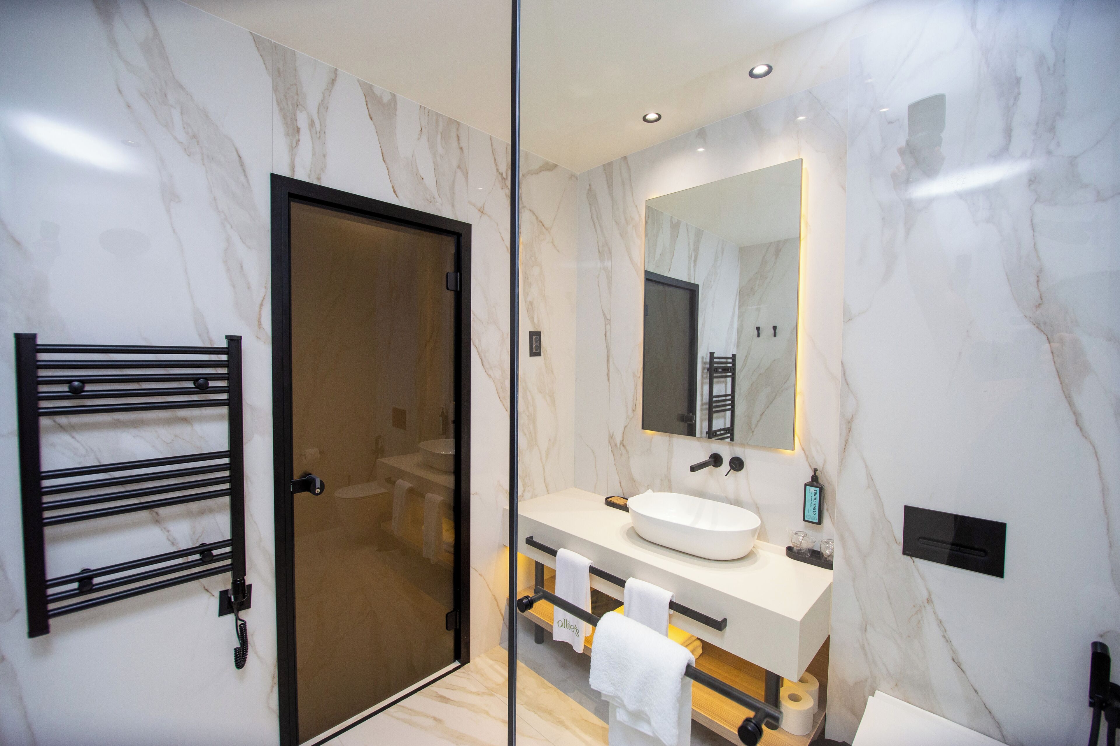 Un baño moderno con cabina de ducha de vidrio, un lavabo blanco y un espejo grande.