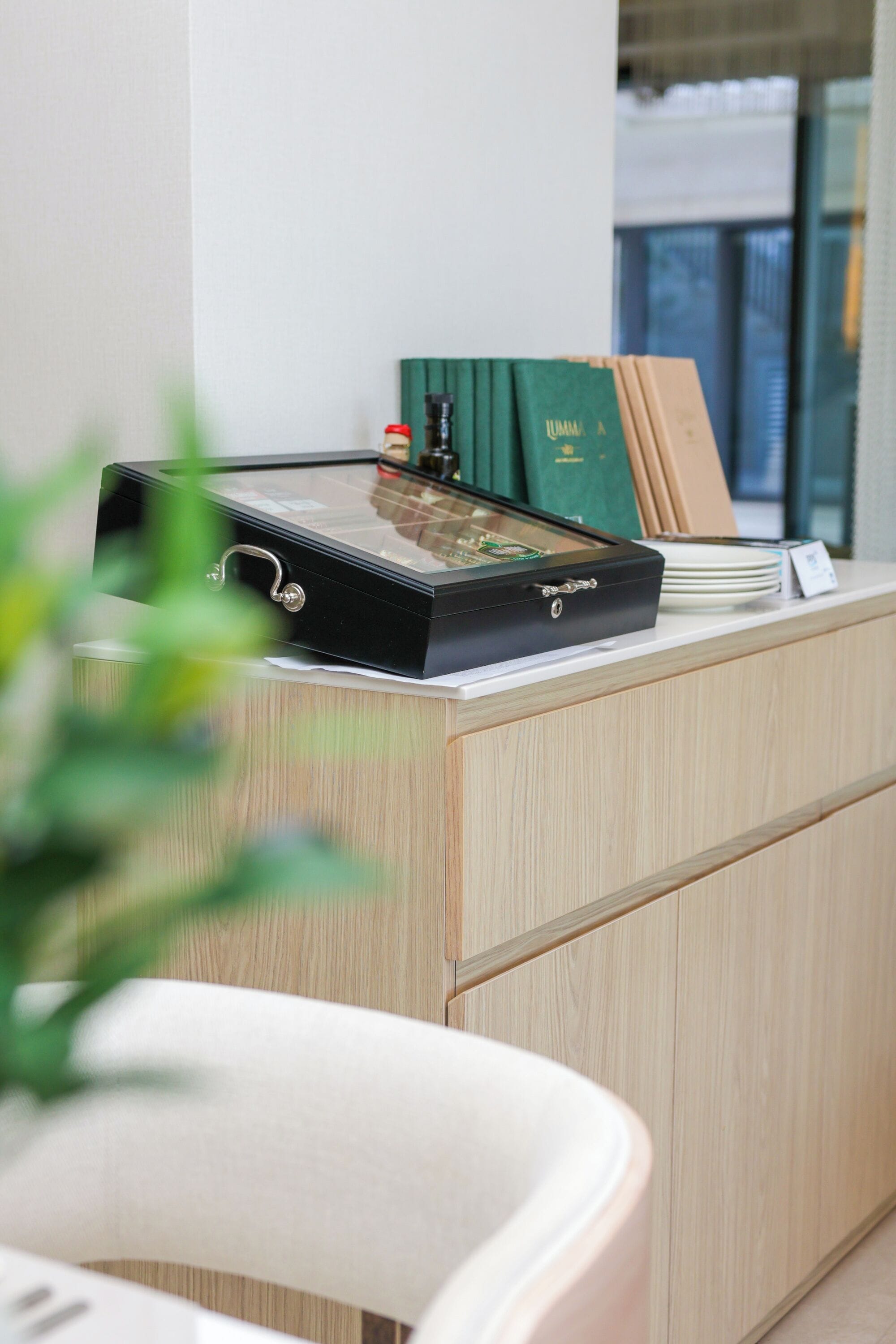 A reception desk with a glass display case, a green book, and a stack of plates.