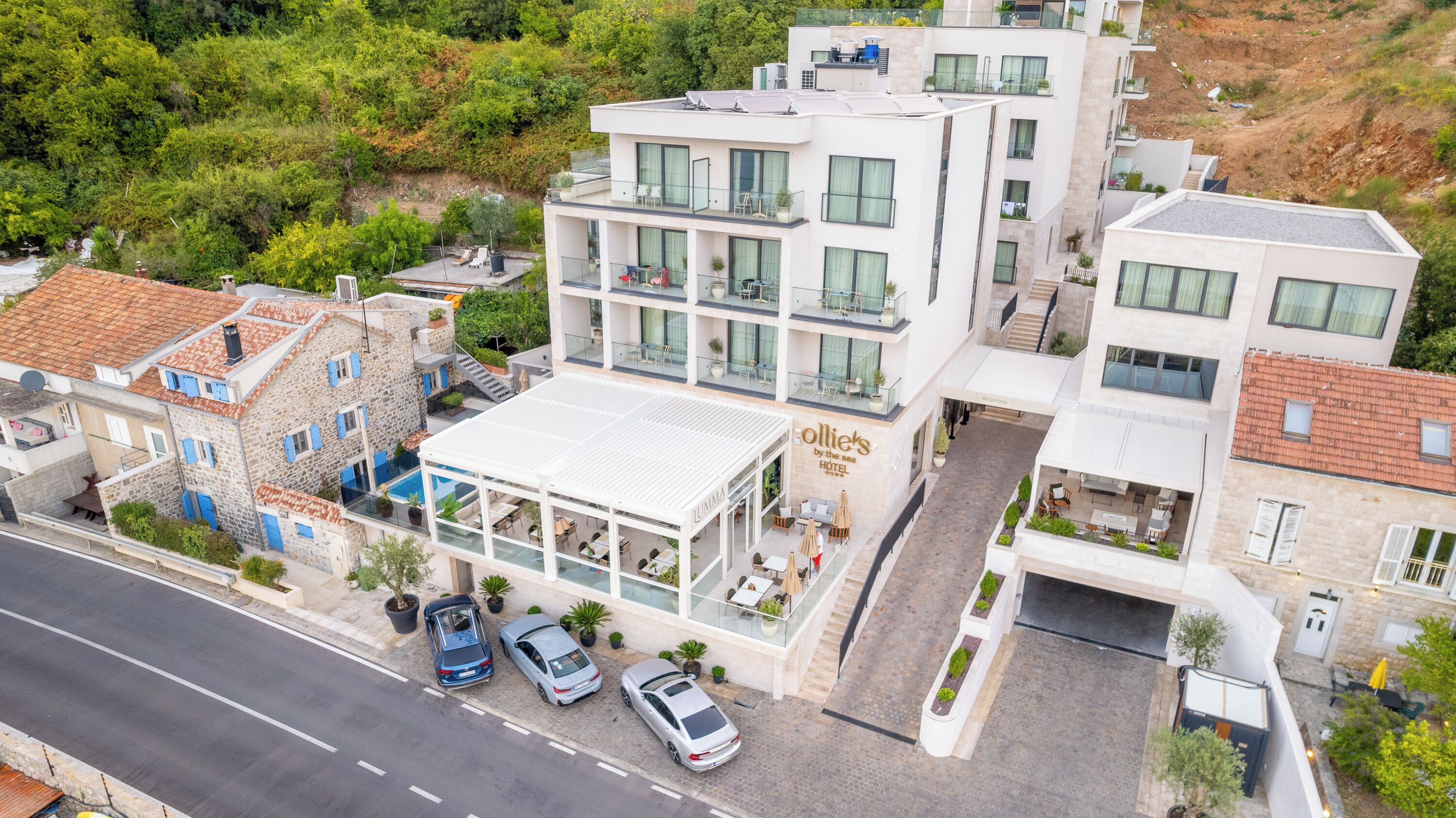 Un hotel con diseño moderno, que cuenta con una terraza en la azotea, una zona de piscina y un mostrador de recepción.