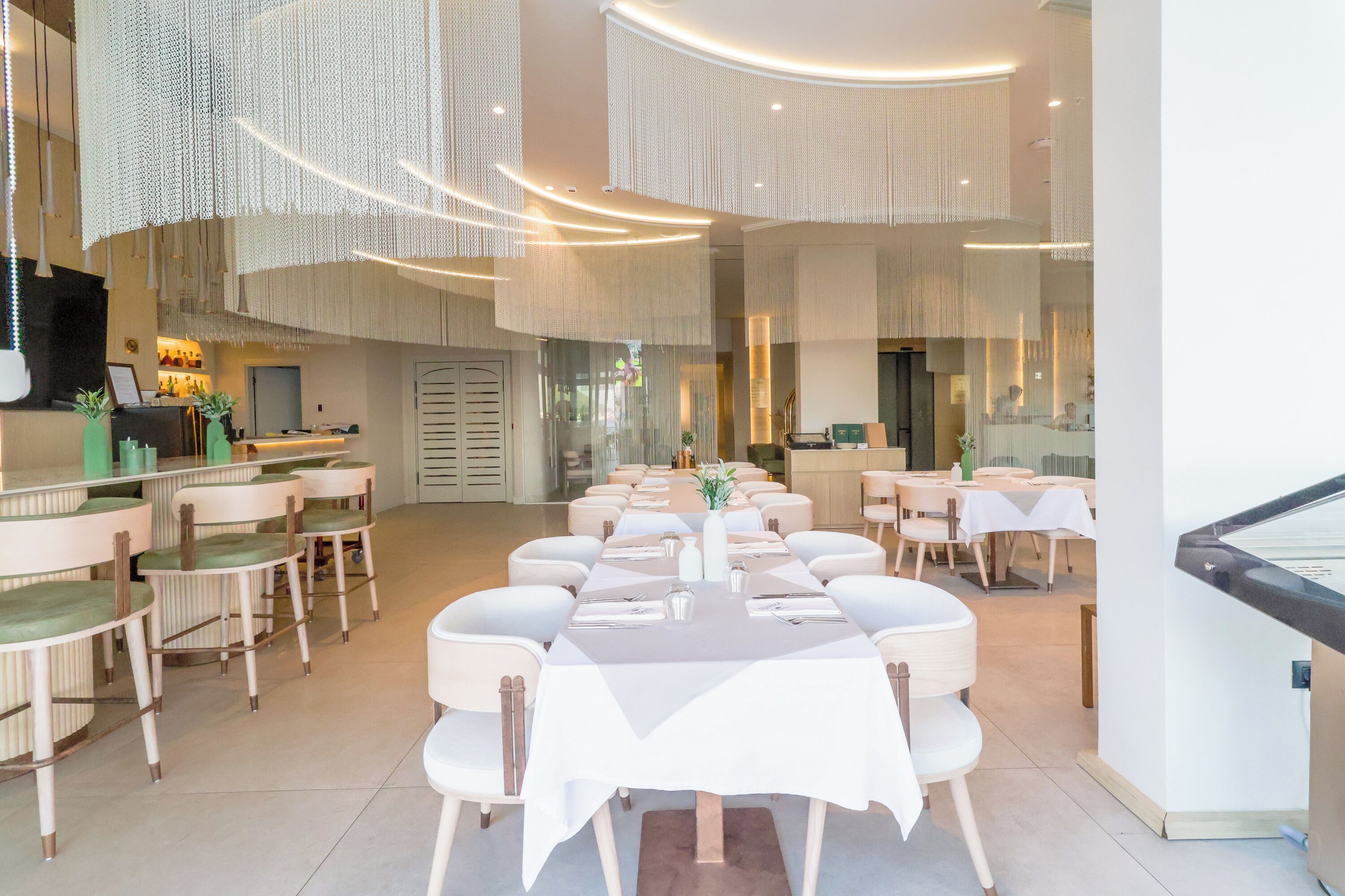 Un restaurante espacioso con techos altos, decoración moderna y diversas opciones de asientos.