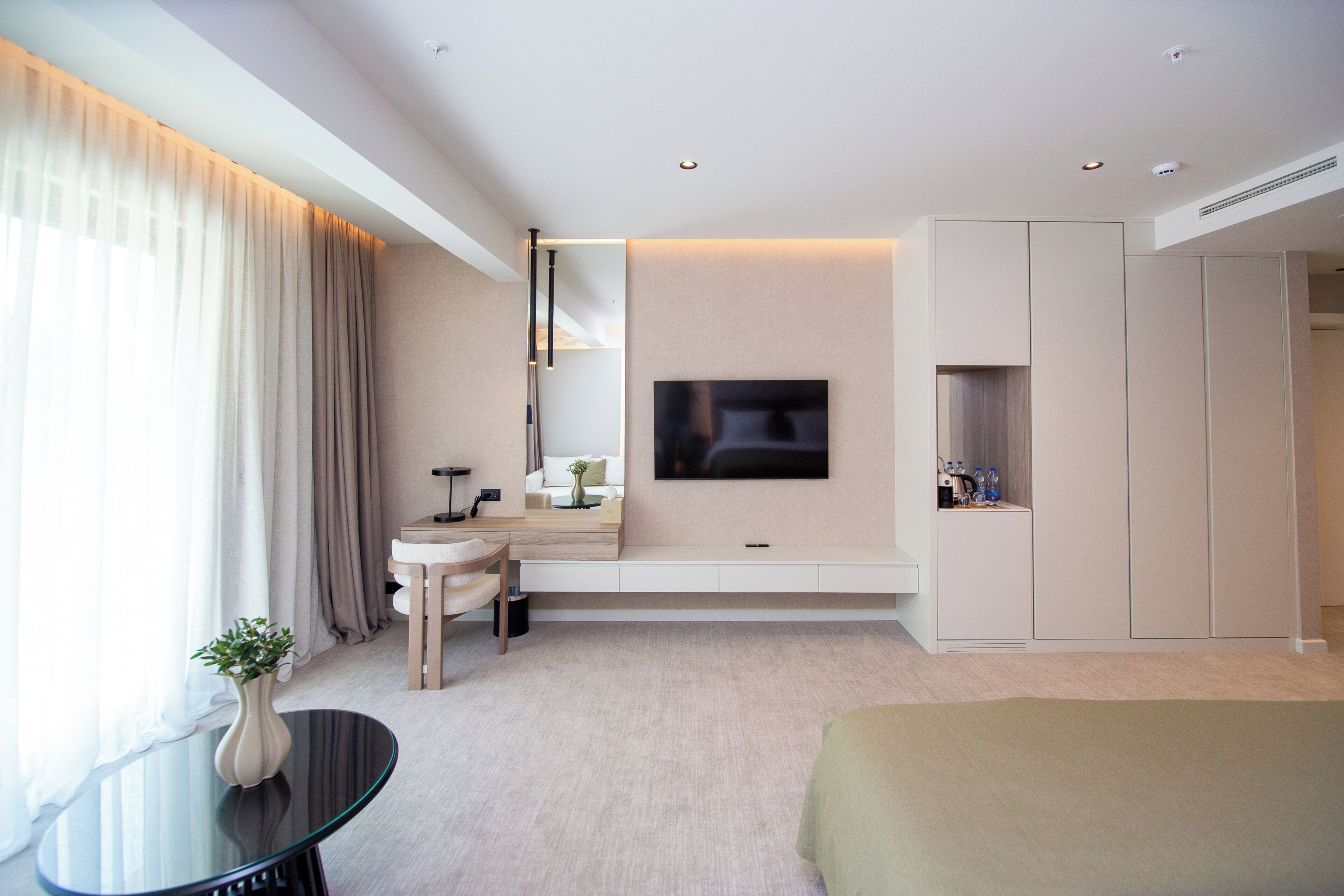 Une chambre d’hôtel moderne équipée d’un lit, d’une télévision, d’une table de chevet, d’un petit canapé, d’un bureau et d’une armoire.
