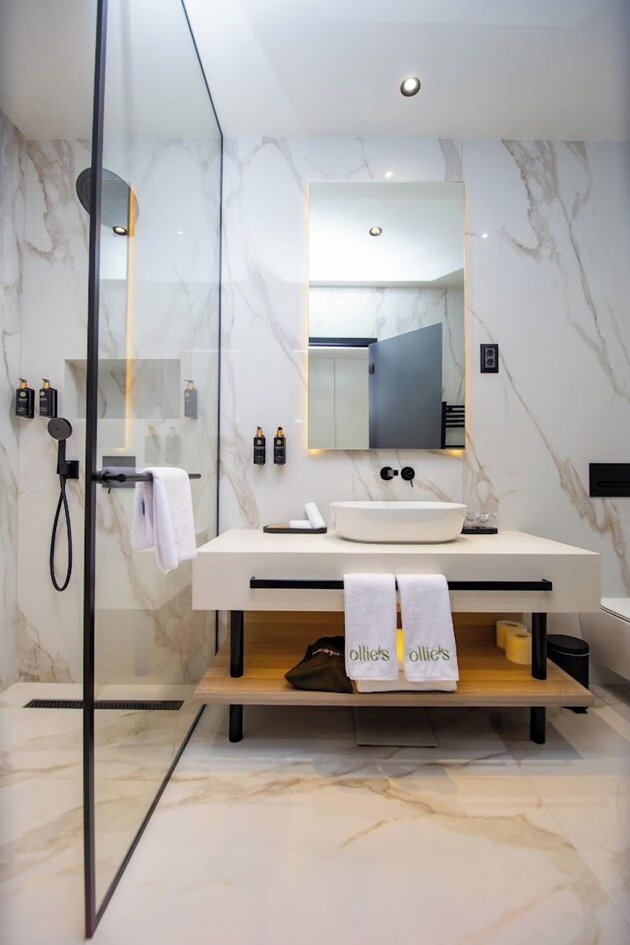 Un baño moderno con cabina de ducha de vidrio, un lavabo blanco y un espejo encima.