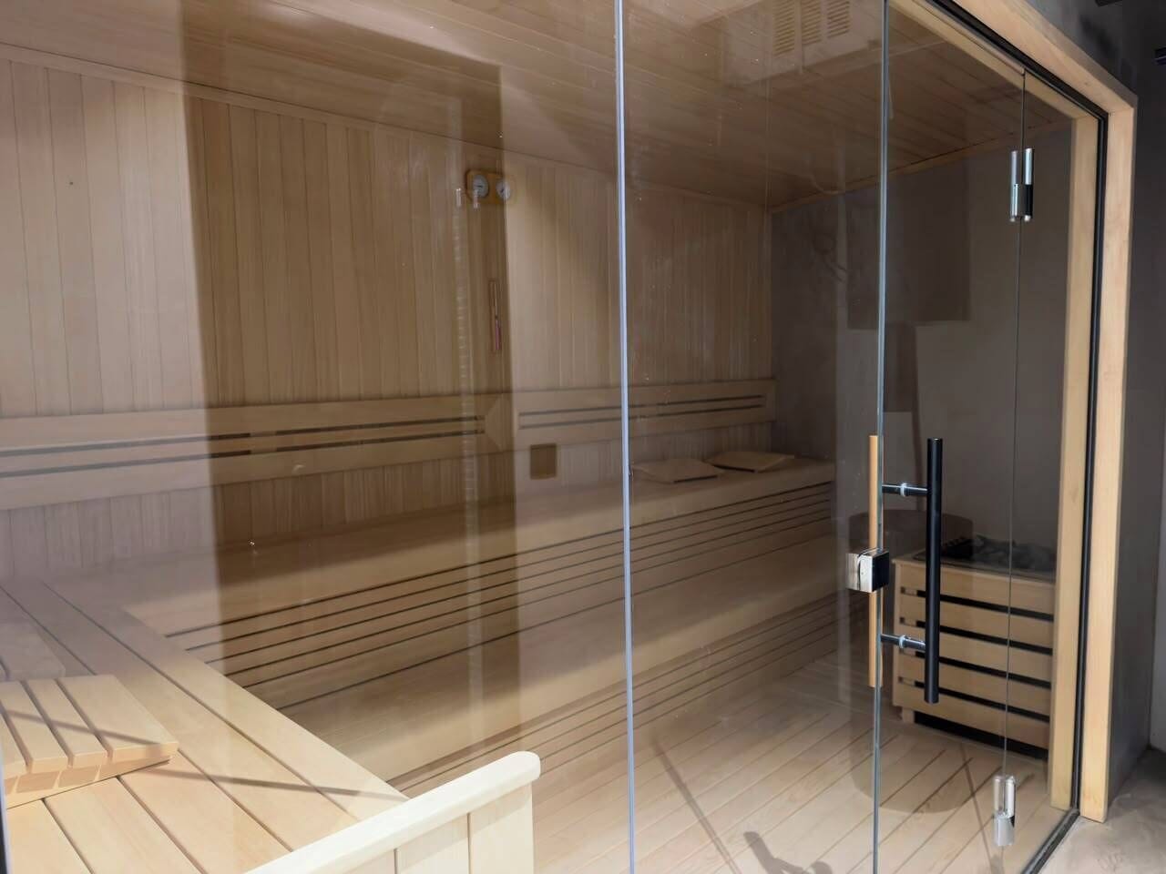 A sauna room with wooden paneling, a glass door, and a wooden bench.