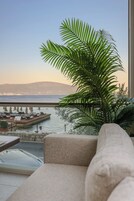 Un salón moderno con un ventanal grande que da a un puerto deportivo y una extensión de agua.