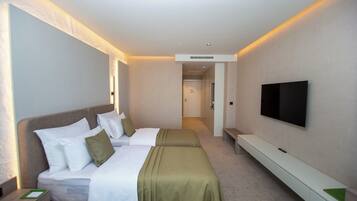 Een hotelkamer met twee bedden, een televisie en een gang naar een andere kamer.