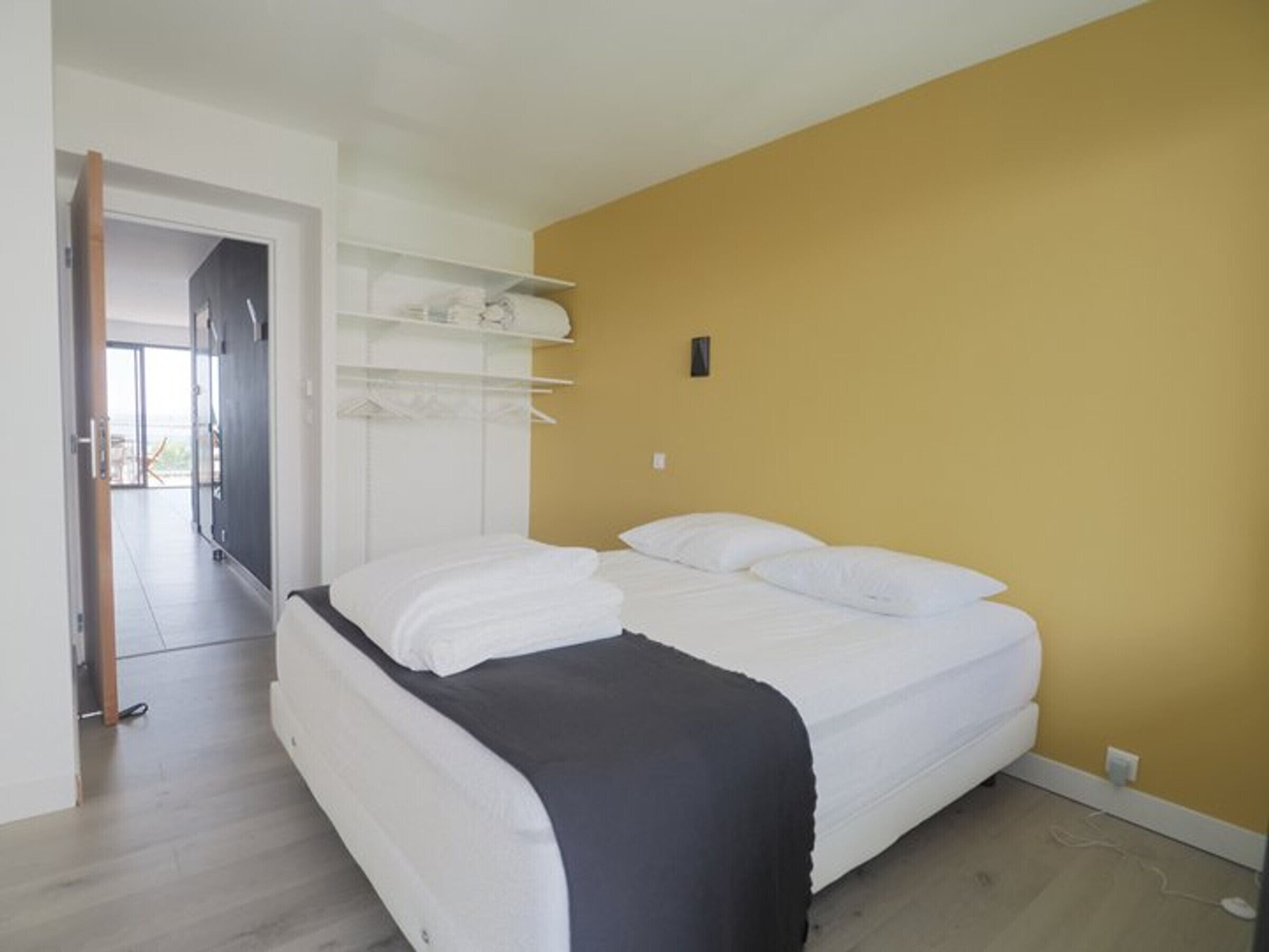 Une chambre à coucher comprenant un lit, une armoire et une porte donnant sur un balcon.
