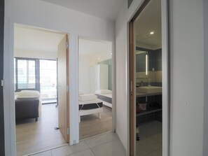 A hotel room with a bed, a small seating area, a bathroom with a mirror, and a view of the outside. - T3 apartment, AC & sea view - 6 guests (La Grande-Motte)