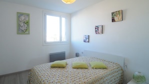 A bedroom with a bed, a radiator, a window, and wall art.