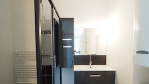 A modern bathroom with a black vanity, white sink, and a mirror above it.