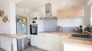 Una cocina moderna con armarios blancos, una campana extractora de acero inoxidable, un microondas y un horno.