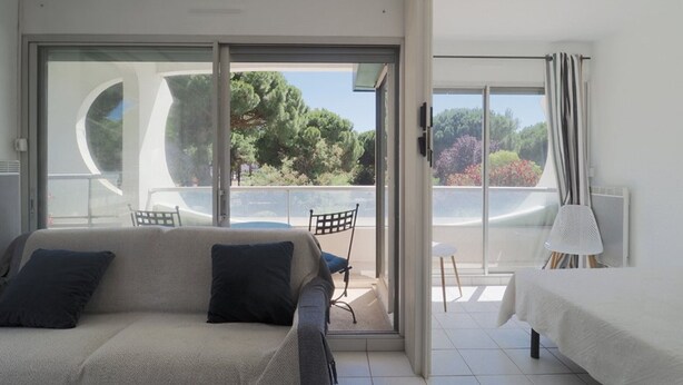 Een slaapkamer met een bed, een bank, een stoel en een balkon met uitzicht op bomen.