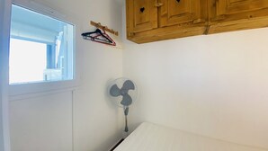 Makuuhuoneessa on ikkuna, tuuletin ja puiset kaapit.