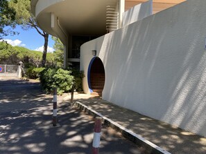 A building with a curved facade, a small entrance, and a bench. - Studio at Boucanet, parking - 4 guests (Le Grau-du-Roi)
