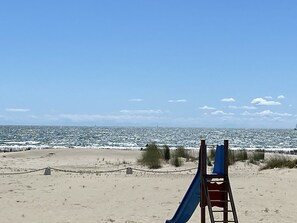 A beach with a lifeguard stand and a blue slide. - Studio at Boucanet, parking - 4 guests (Le Grau-du-Roi)