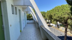 Un balcon incurvé doté d’un sol carrelé, donnant sur une route bordée d’arbres et s’ouvrant sur un ciel dégagé.