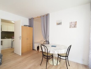 A compact room with a bed, a small table, and a kitchenette in the background. - Spacious studio in city center - 4 guests (La Grande-Motte)