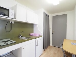 A compact kitchen with a microwave, sink, and a small table. - Spacious studio in city center - 4 guests (La Grande-Motte)