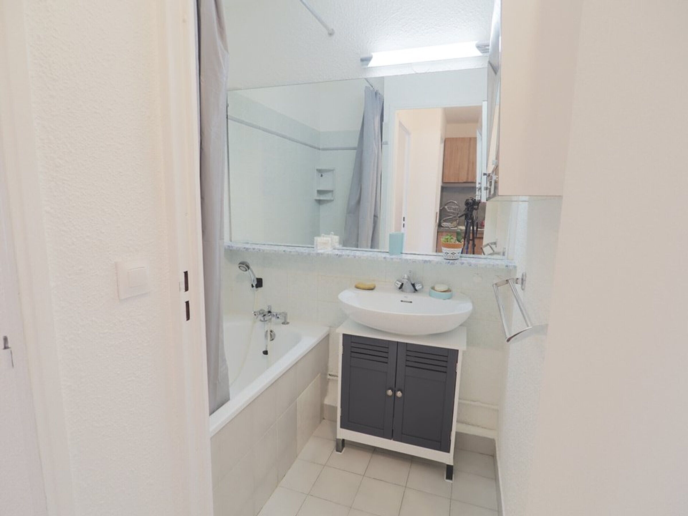 A compact bathroom with a bathtub, a sink, and a mirror.