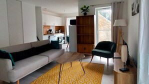 A modern living room with a sofa, a small coffee table, a chair, a bookshelf, and a lamp. - New apartment in the heart of Le Palais (Le Palais)