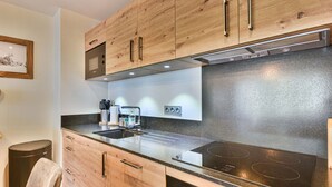 Eine moderne Küche mit Holzausstattung, einer Edelstahl-Dunstabzugshaube und einem eingebauten Backofen.