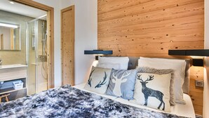 Ein Schlafzimmer mit einem hölzernen Kopfende, einem Bett mit gemusterten Betttextilien, einem Nachttisch und einem Spiegel.