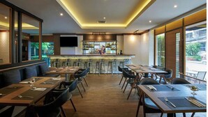 Un restaurante con barra, varias mesas y sillas.