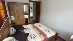 A bedroom with a bed, a nightstand, a lamp, a wardrobe, and a door leading to another room. - 120 La Molina · Panoramic Views 5 Minutes From La Molina Ski Resort (Alp)